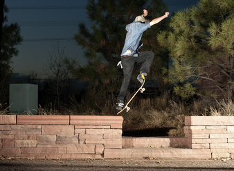 Seitenansicht eines Mannes, der nachts mit dem Skateboard springt - CAVF06268