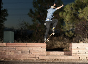 Side view of man jumping with skateboard at night - CAVF06268