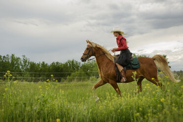 Seitenansicht von Frau reitet auf Pferd gegen Wolken Himmel - CAVF06278