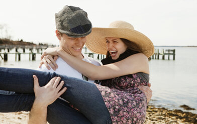 Man lifting woman while walking at beach - CAVF06306