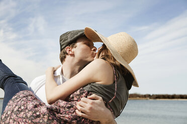 Mann küsst Freundin beim Tragen am Strand - CAVF06307