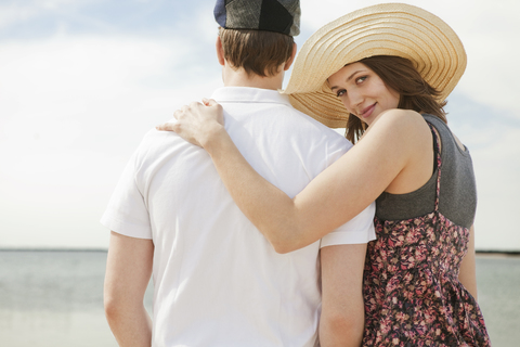 Porträt einer Frau, die mit einem Mann am Strand spazieren geht, lizenzfreies Stockfoto