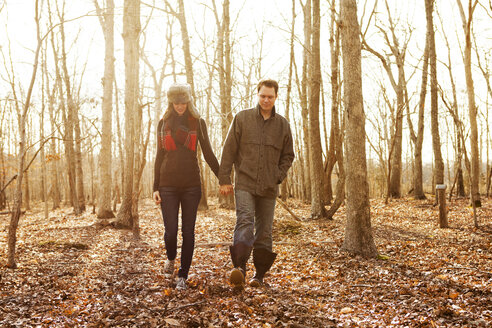 Paar hält Hände beim Spaziergang im Wald - CAVF06359