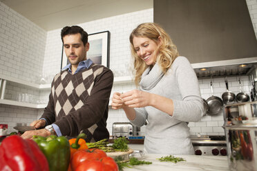 Low angle view of couple chopping vegetables in kitchen - CAVF06368