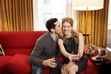 Happy man kissing girlfriend holding wineglass - CAVF06374