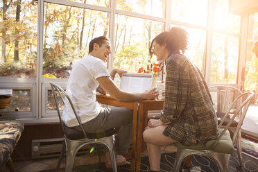 Cheerful couple using laptop while sitting at table in home - CAVF06448