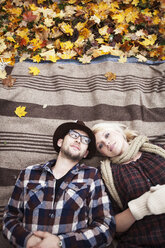 Overhead view of couple lying on blanket at field - CAVF06476