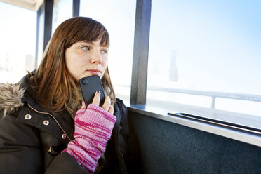 Frau mit Mobiltelefon, die während der Fahrt in einer Fähre wegschaut - CAVF06482