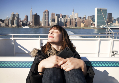 Woman relaxing while traveling in ferry against buildings stock photo