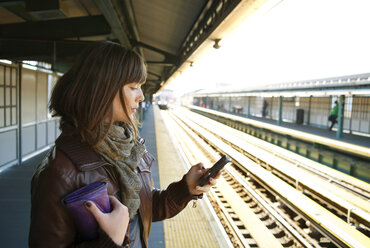 Frau benutzt ihr Smartphone auf dem Bahnsteig - CAVF06488