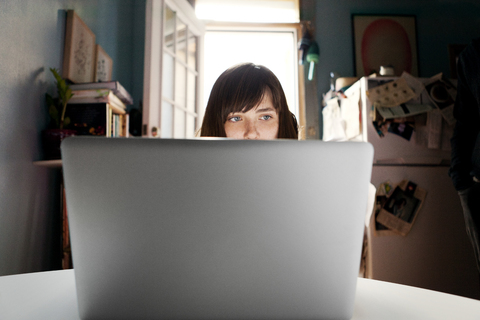 Woman using laptop computer while sitting by table at home stock photo