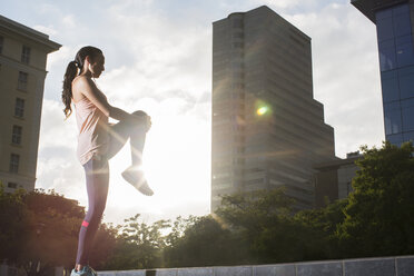 Woman stretching before exercising on city street - CAIF15165