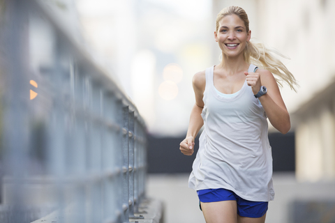 Woman running through city streets stock photo