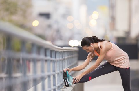 Frau dehnt sich vor dem Training auf einer Straße in der Stadt, lizenzfreies Stockfoto