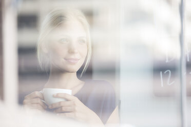 Frau trinkt Kaffee in einem Haus - CAIF15183