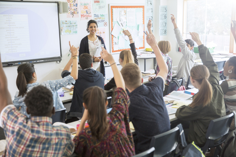 Rückansicht von jugendlichen Schülern, die im Klassenzimmer die Hände heben, lizenzfreies Stockfoto