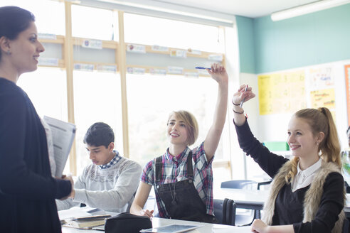 Schüler mit ihrem Lehrer im Klassenzimmer, lächelnd und mit erhobenen Armen - CAIF15212