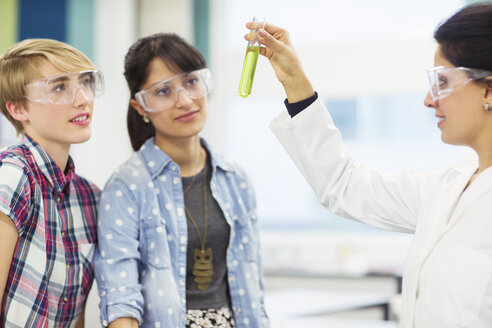 Schüler mit ihrem Lehrer bei der Arbeit im Chemielabor, Lehrer hält Reagenzglas mit grüner Flüssigkeit - CAIF15216