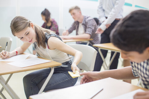 Schüler reichen während ihrer GCSE-Prüfung Zettel zwischen den Tischen weiter - CAIF15231