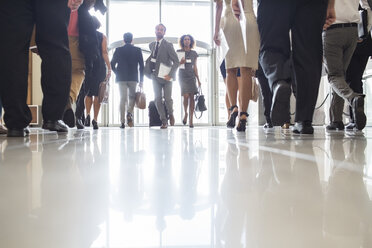 Business people rushing through office hall, reflections on tiled floor - CAIF15236