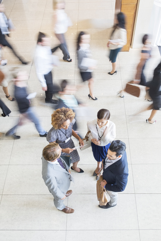 High-Winkel-Ansicht von Business Menschen stehen im Büro, im Gespräch und lächelnd, lizenzfreies Stockfoto