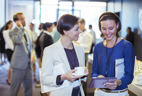 Porträt von zwei lächelnden Frauen, die sich in der Lobby eines Konferenzzentrums während einer Kaffeepause unterhalten - CAIF15271