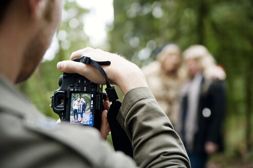 Ausgeschnittenes Bild eines Mannes, der im Wald stehend Frauen fotografiert - CAVF06545