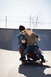 Vater bringt seinem Sohn im Park das Skateboardfahren bei - CAVF06552