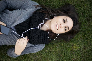 Overhead view of woman looking away while relaxing on grassy field - CAVF06560