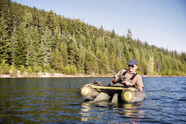 Happy man fishing while sitting on pontoon boat in lake - CAVF06582