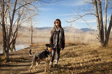 Frau mit Hund stehend auf Feld gegen Himmel - CAVF06617