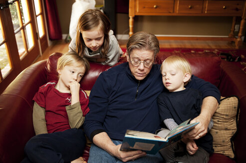 Großvater erzählt Kindern Geschichten, während er zu Hause auf dem Sofa sitzt - CAVF06669