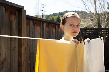 Porträt eines Mädchens, das eine Wäscheleine hält, während es im Hinterhof steht - CAVF06671