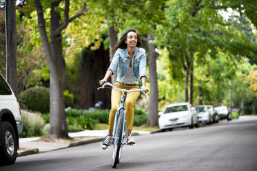 Woman looking away while riding bicycle on street - CAVF06687