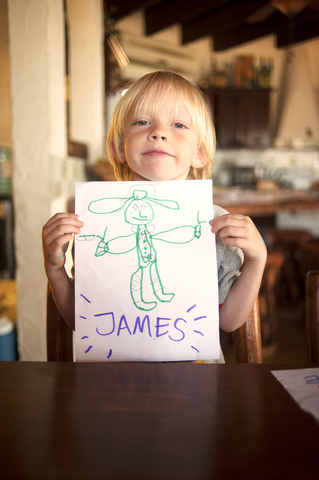 Porträt eines glücklichen Jungen, der eine Zeichnung zeigt, lizenzfreies Stockfoto