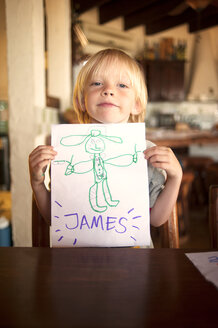 Porträt eines glücklichen Jungen, der eine Zeichnung zeigt - CAVF06738