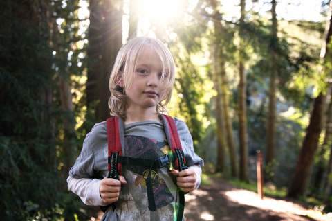 Porträt eines Jungen mit Rucksack im Wald stehend, lizenzfreies Stockfoto