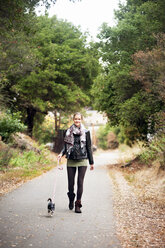 Portrait of woman with dog walking on road - CAVF06810