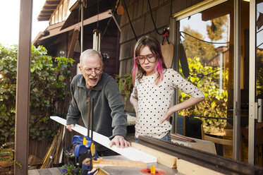 Girl looking at carpenter working at workshop - CAVF06815