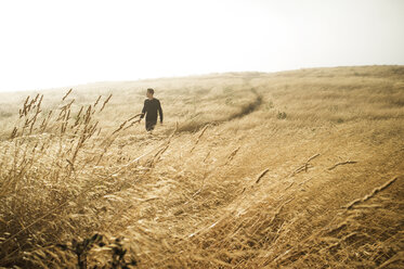 Man walking on grassy field against clear sky - CAVF06849