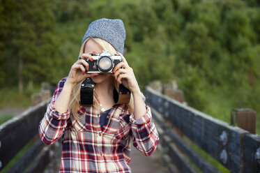 Frau fotografiert mit Kamera auf einer Brücke stehend - CAVF06923