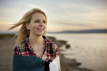 Happy woman looking away while standing at beach during sunset - CAVF06925