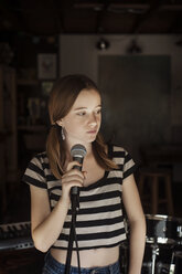 Girl looking away while standing by microphone - CAVF06939