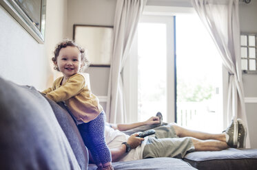 Glückliches kleines Mädchen mit Vater auf dem Sofa zu Hause - CAVF06965