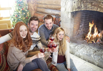 Friends celebrating with drinks in log cabin - CAIF15292