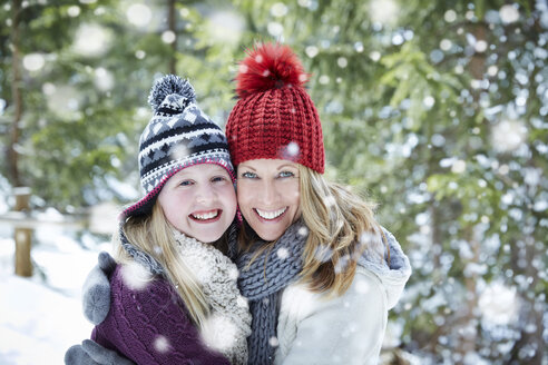 Mutter und Tochter umarmen sich im Schnee - CAIF15386