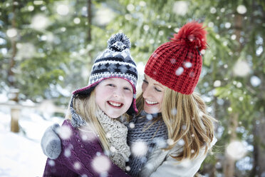 Mother and daughter hugging in the snow - CAIF15389