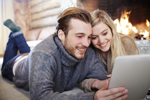Ehepaar benutzt digitales Tablet am gemeinsamen Kamin, lizenzfreies Stockfoto
