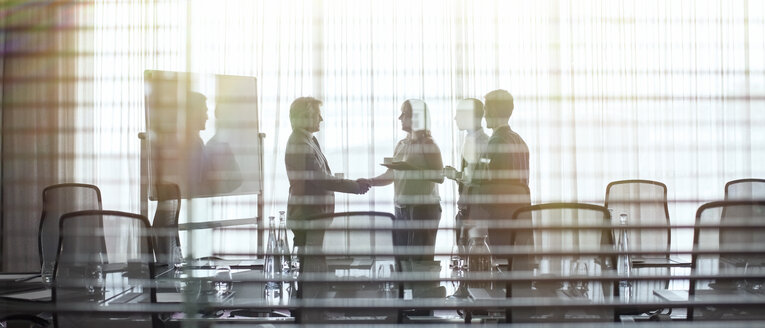 Business people standing in conference room shaking hands - CAIF15418