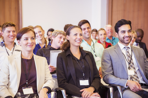 Geschäftsleute, die in einem Konferenzraum sitzen, lächeln und wegschauen, lizenzfreies Stockfoto